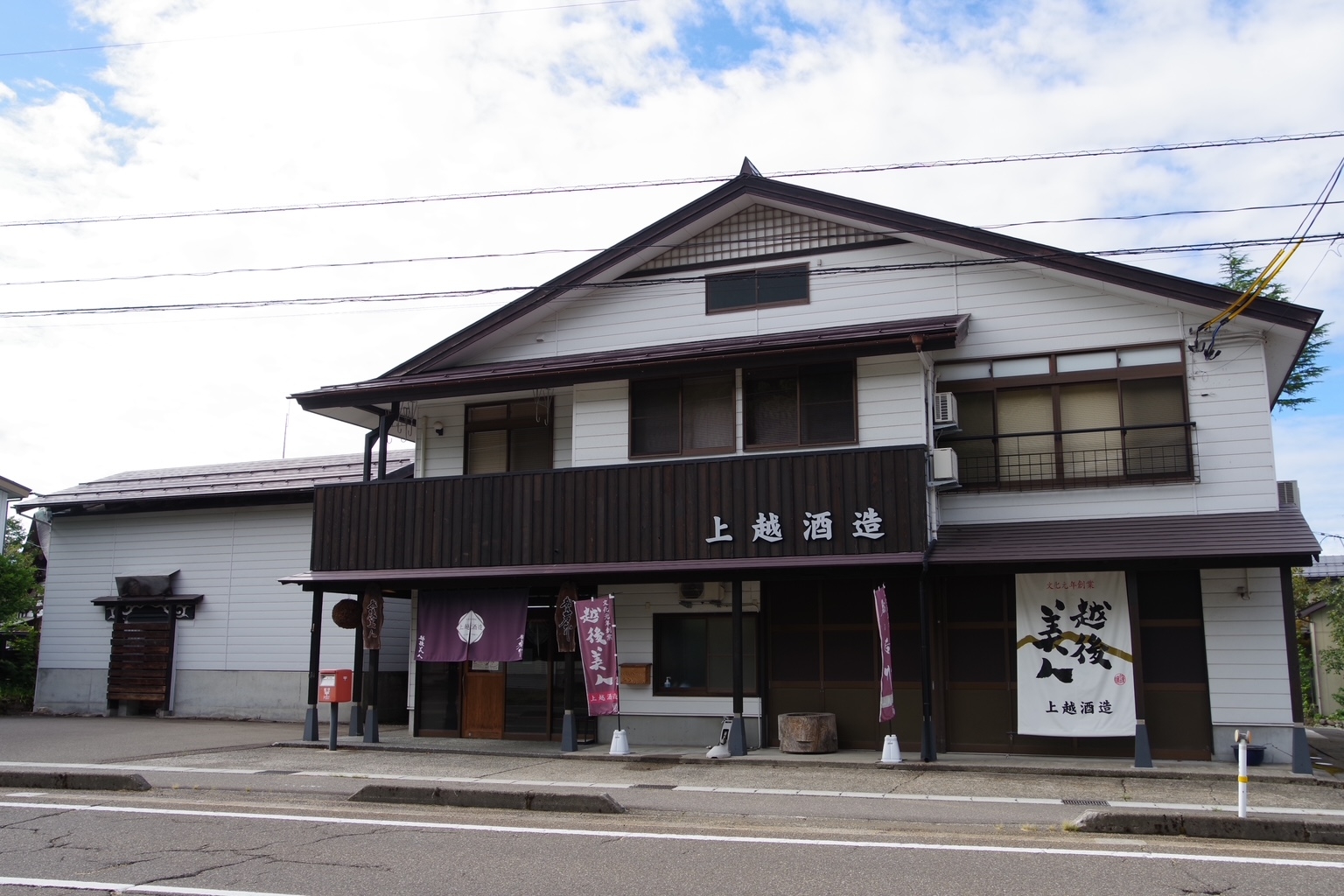 上越酒造の正面。白壁の建物に「上越酒造」の看板と「越後美人」の暖簾